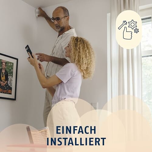 Zwei Personen installieren ein Gerät an der Wand.